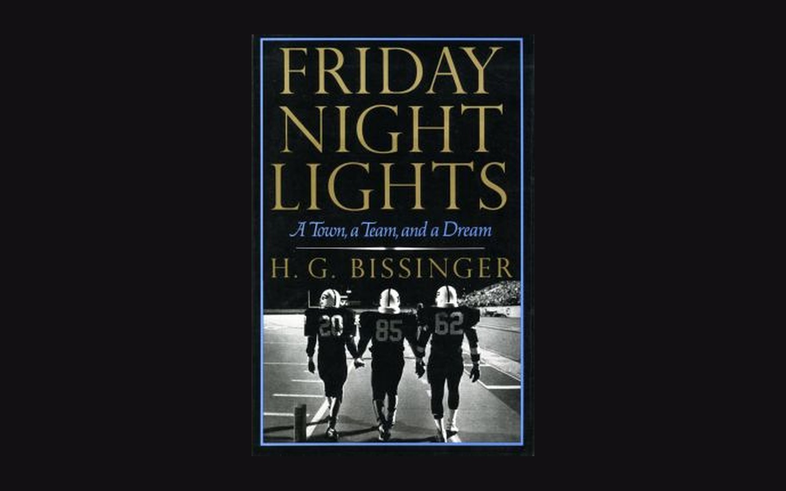 The 1990 Friday Night Lights book jacket by H. G. Bissinger lying on a wooden table, photographed from above