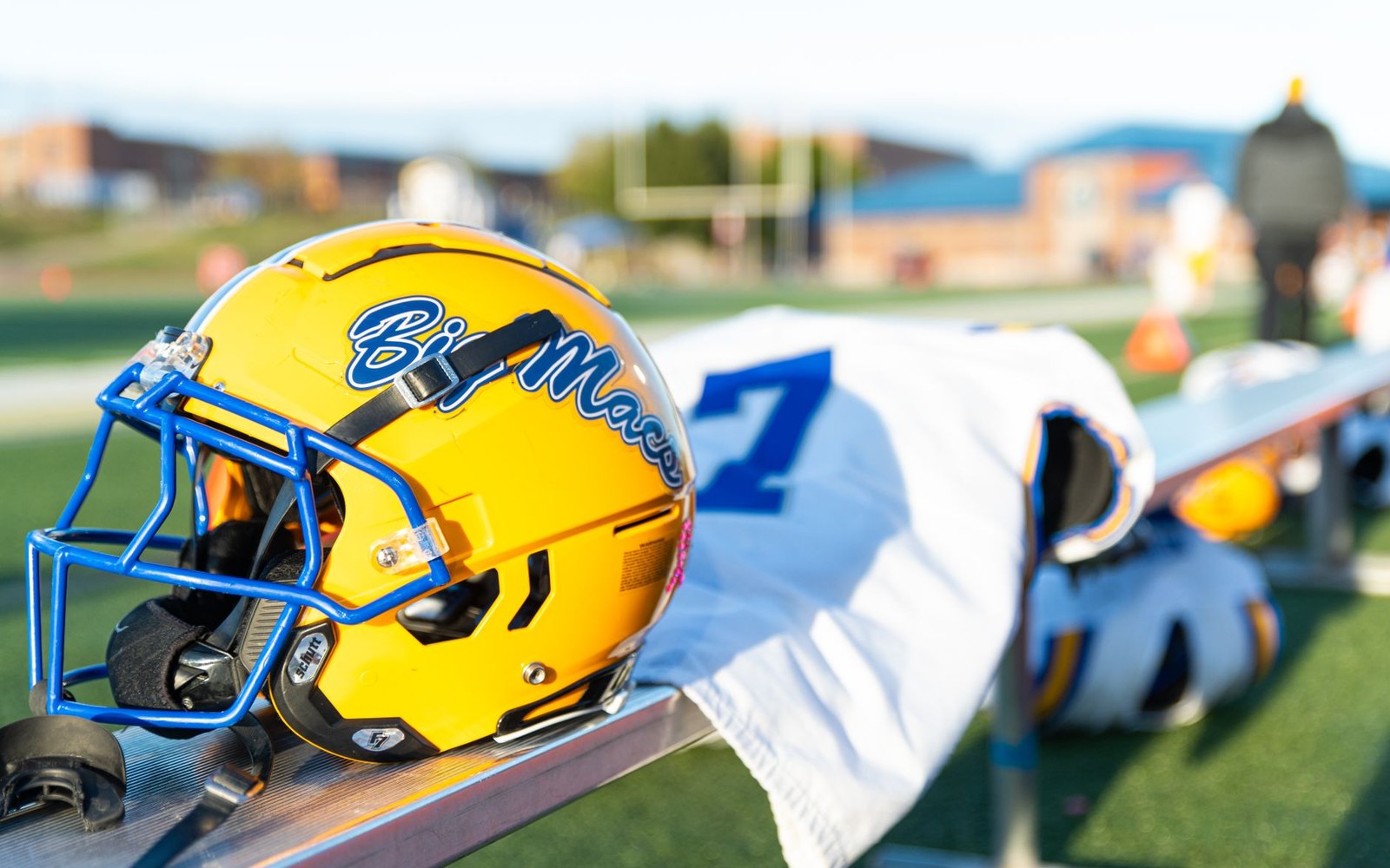 A yellow "Big Maroon" football helmet resting on a bench beside a numbered jersey