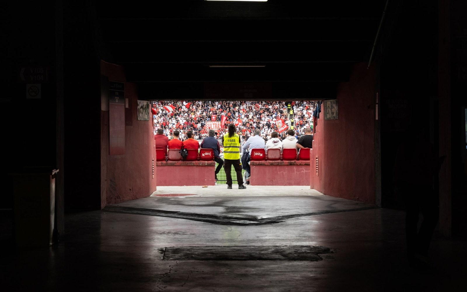 Stadium tunnel view of red-and-white clad fans filling the stands beyond