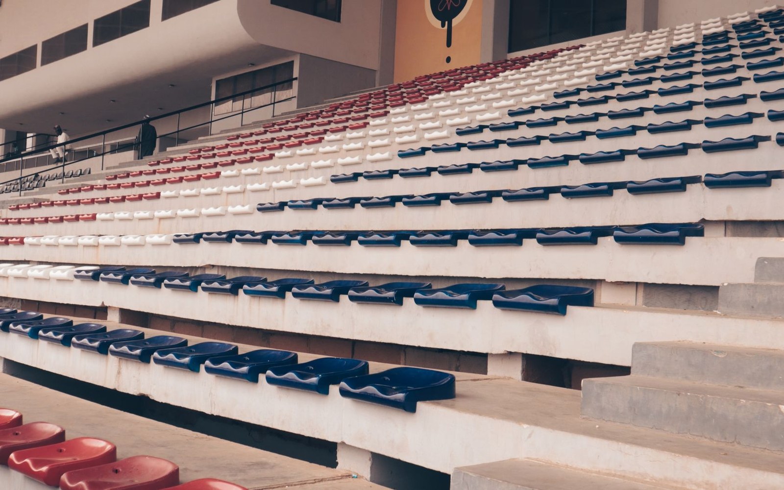 Empty stadium bleachers with rows of red, white, and blue plastic seats