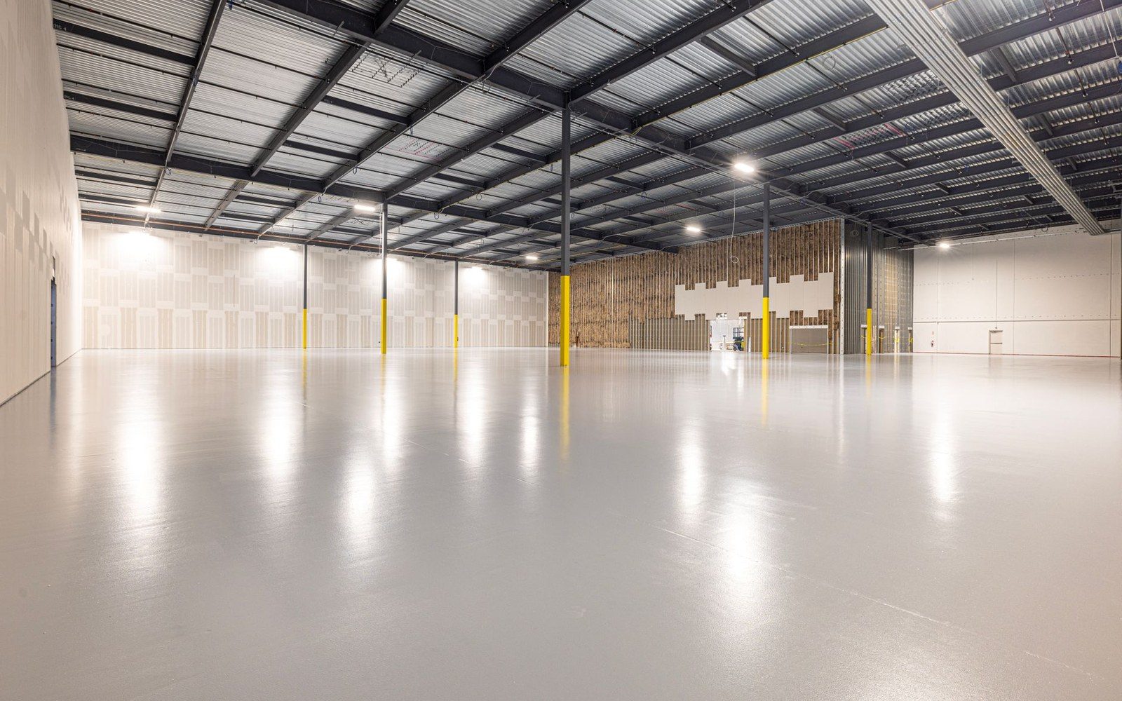 Empty warehouse interior with polished concrete floor and yellow support columns