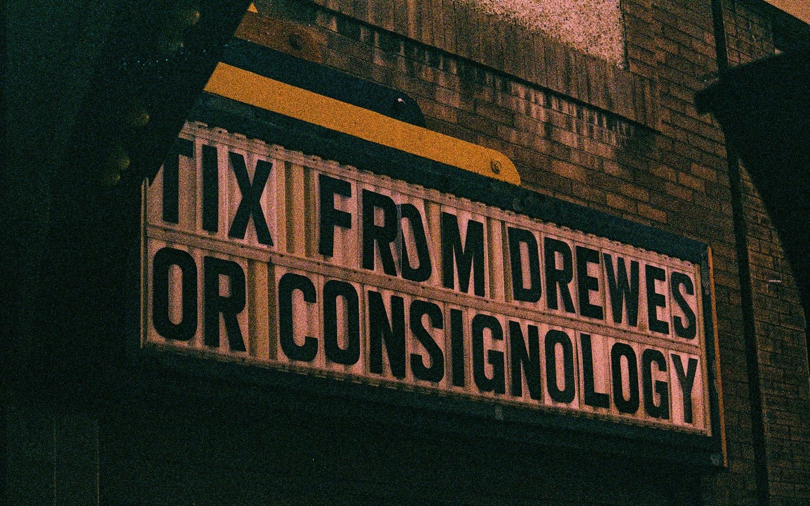 Marquee sign reading "tix from Drewes or Consignology" mounted on a brick building