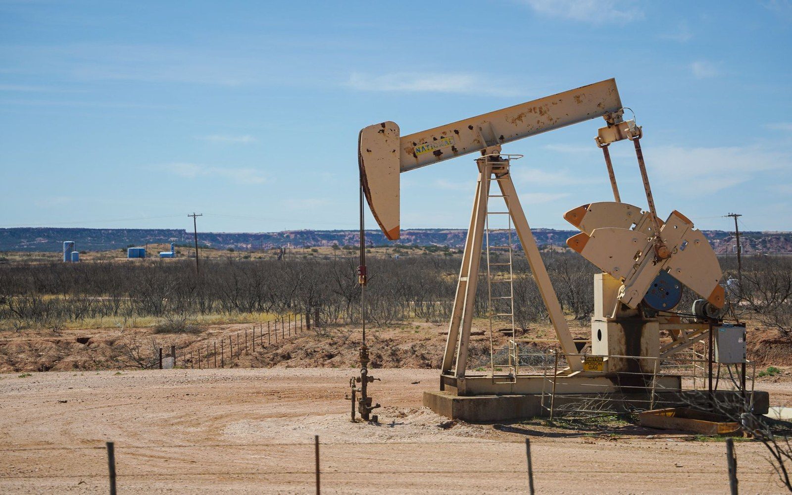 An Odessa street at dusk with pumpjacks silhouetted against a flat West Texas sky in the background