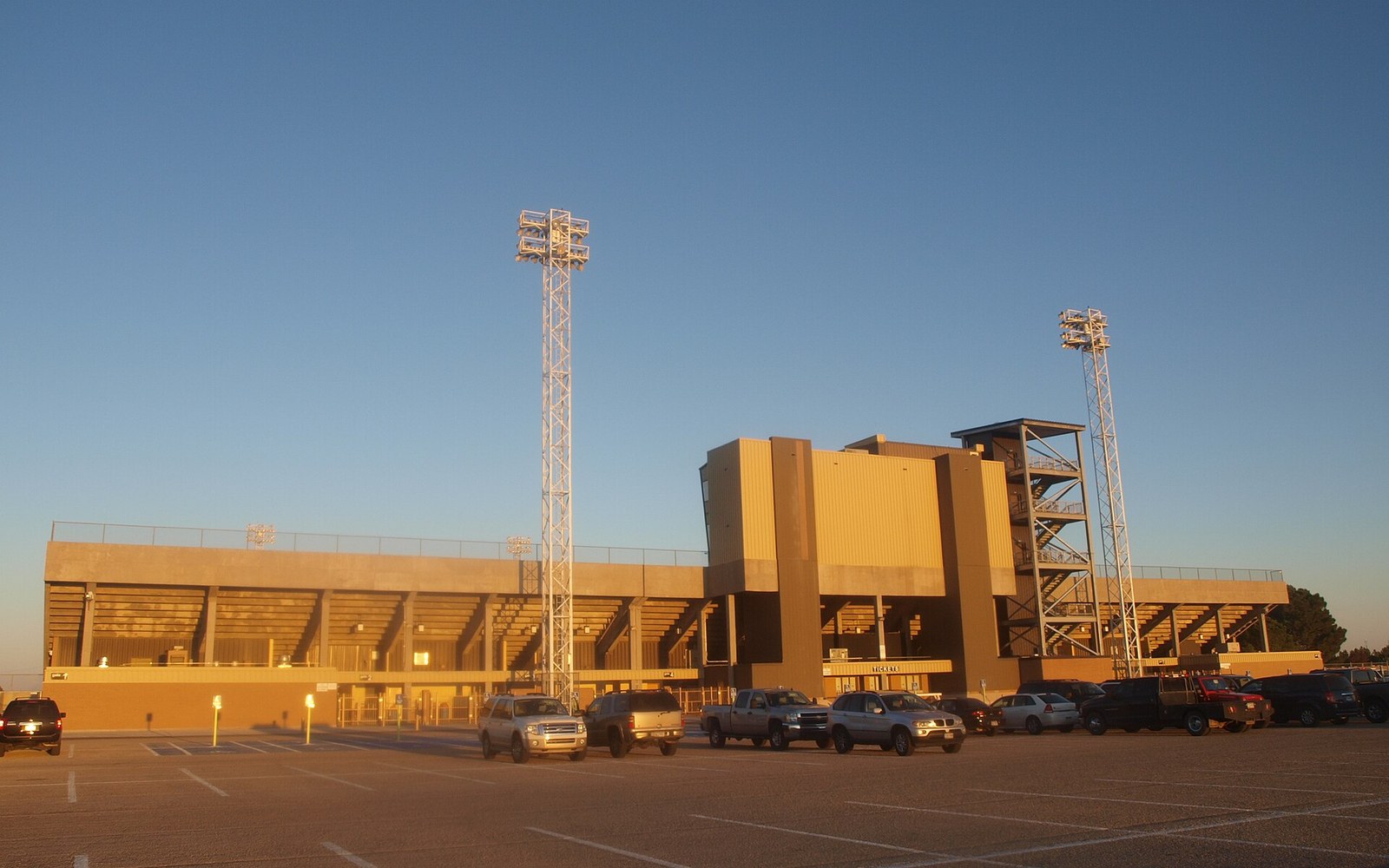Empty Ratliff Stadium at dusk, seen from the west stands with floodlights beyond the field